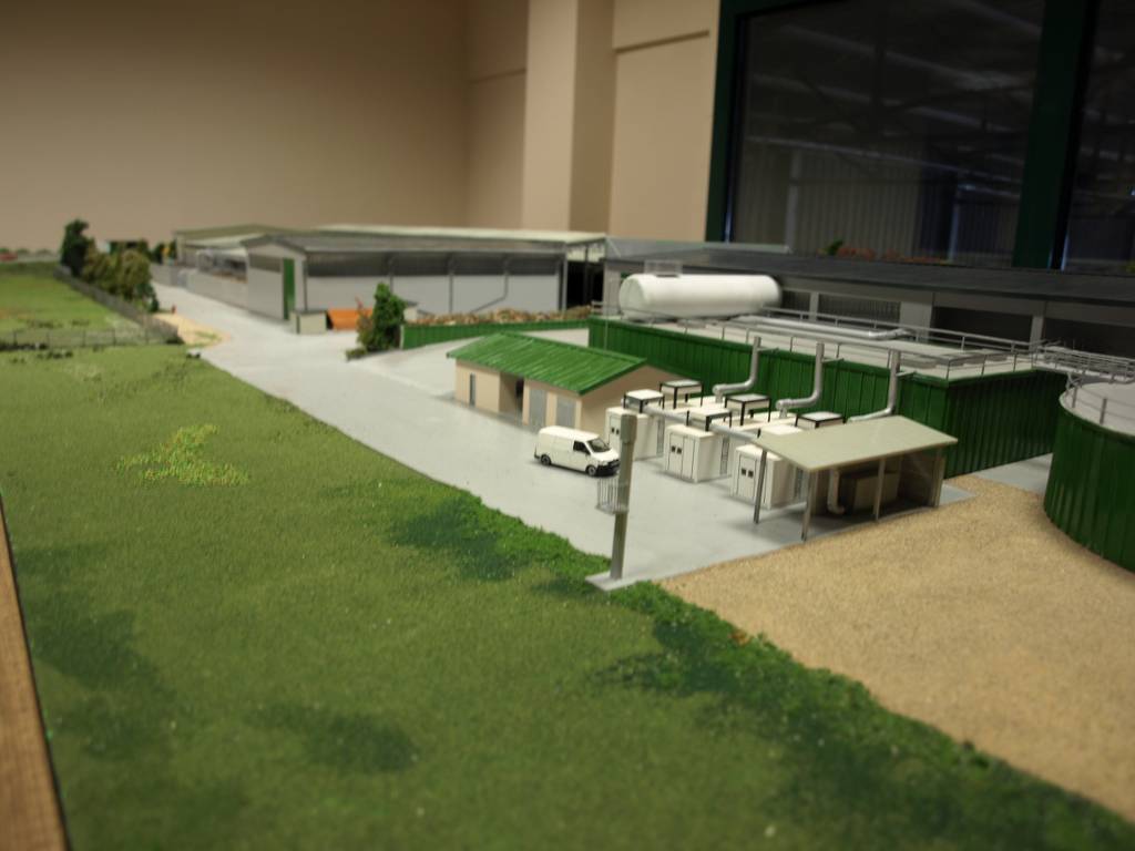 Modello in scala di un impianto industriale con strutture verdi e un cortile, circondato da aree verdi.