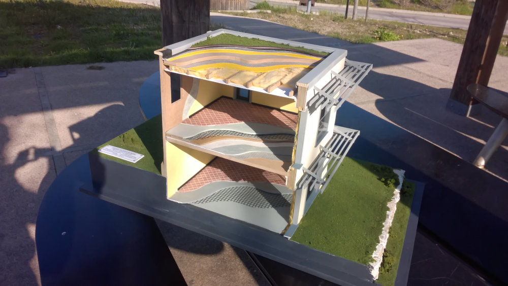 Modello in scala di sezione stradale con strati di terra e materiali di costruzione esposto all'aperto.